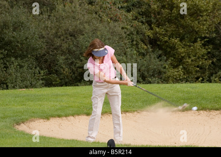 Signora donna femmina persona golfista giocando un bunker Shot Foto Stock