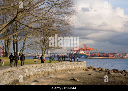 La gente che camminava sul Seawall a Stanley Park con Centerm terminale per container al di là di Vancouver British Columbia Canada Foto Stock