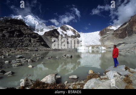 Trekker guardando a vista in Laguna Glaciar, Monte Illampu in background, Cordillera Real, Bolivia Foto Stock
