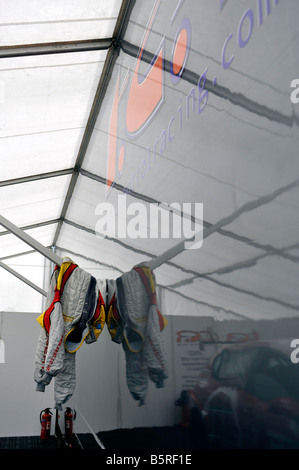 Driver racing Tute appeso in auto racing pit marquee Foto Stock