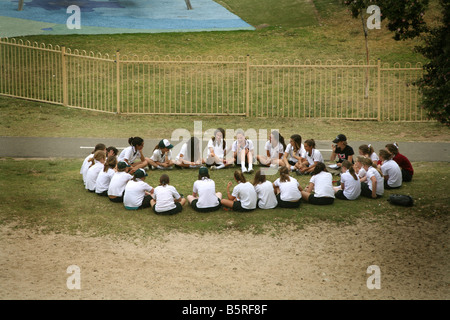 Una classe di studentesse di sedersi con il loro insegnante all'aperto, in una ambiente di istruzione Foto Stock