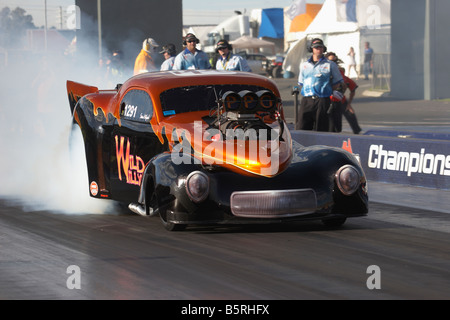 Australian Top Doorslammer drag racing concorrente, Sean Mifsud, esegue un rolling burnout nel suo 1941 basato Ford Willys coupe Foto Stock