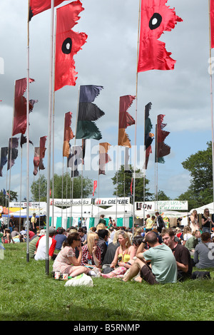 Glastonbury Festival giugno 2008 i frequentatori del festival i fan di rilassarsi con una birra fra le bandiere Foto Stock