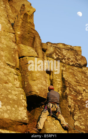 Rocciatore sul bordo Froggatt Derbyshire Peak District a fine febbraio Foto Stock