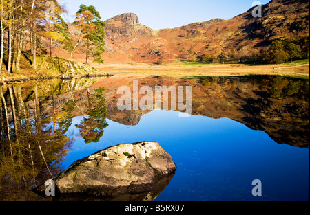 La mattina presto e il sole riflessioni in Blea Tarn su una soleggiata giornata autunnale, Parco Nazionale del Distretto dei Laghi, Cumbria, England, Regno Unito Foto Stock