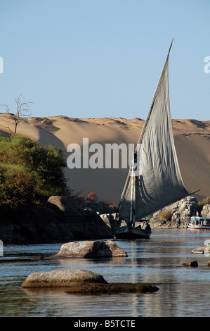 Felucca tradizionale barca a vela lungo il fiume Nilo e la prima cataratta con il deserto occidentale sullo sfondo in Assuan Sud Egitto Foto Stock