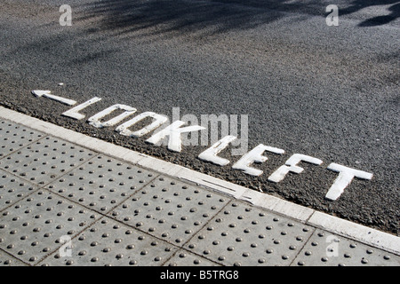 Guardare a sinistra segno dipinto sulla strada di attraversamento Foto Stock