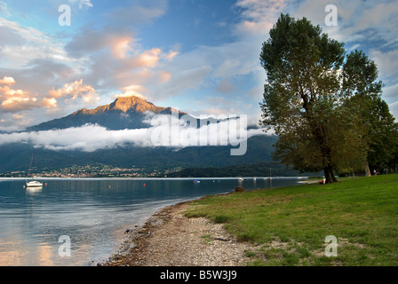 Sera sun colpisce un picco di montagna alle spalle di Domaso sul Lago di Como in Lombardia, Italia. Foto Stock