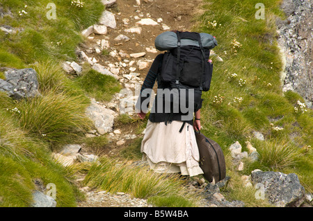 La donna che porta un pacco pesante e una chitarra ad alta altitudine sul crinale di Robert, Nelson Lakes National Park, Nuova Zelanda Foto Stock