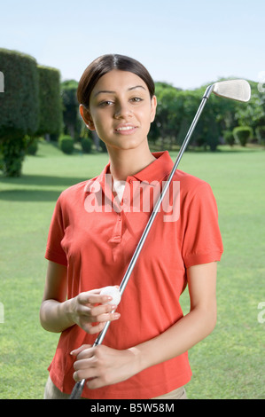 Donna che mantiene un golf club e di una pallina da golf Foto Stock