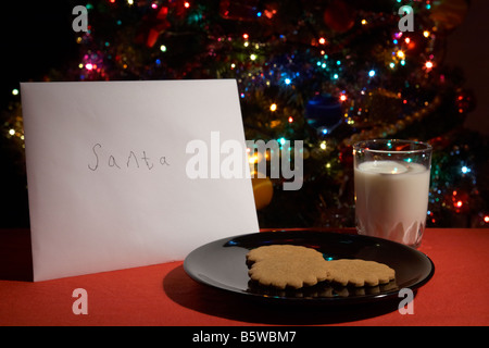 Childs lettera a Babbo lasciato fuori alla vigilia di Natale con i cookie e bicchiere di latte nella parte anteriore dell albero di natale Foto Stock