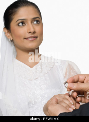 Close-up di uno sposo la mano collocando un anello al dito della sposa Foto Stock