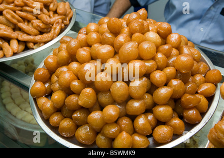 Pelo di palle dolci e croccanti di pasta fritta imbevuta di sciroppo chiamato awama o awamat per la vendita in un negozio di pasticceria Cairo Egitto Foto Stock