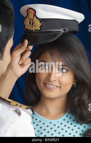 Navy officer regolazione cappuccio uniforme su una giovane testa di donna Foto Stock