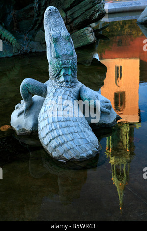 Statua di coccodrillo presso la fontana del Nettuno con la riflessione del XIII secolo la torre campanaria della chiesa di Santa Maria in acqua a Berlino, Germania Foto Stock