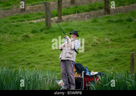 Maschio anziano pescatore angling uomo la pesca sul lago Foto Stock