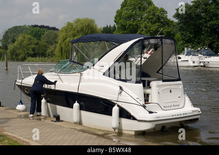 Barca a motore barca ormeggiata in un posto barca sul fiume Tamigi a Molesey Foto Stock