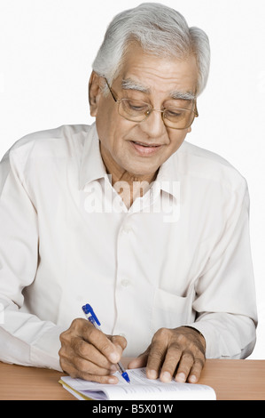 Senior uomo la scrittura su un blocco note Foto Stock