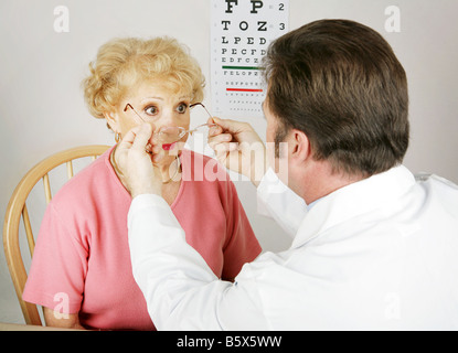 Senior donna che sta provando una nuova prescrizione dal suo all'ottico optometrista Foto Stock