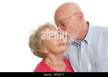 Un attraente uomo senior di baciare la sua bella moglie sulla guancia isolato con una stanza per il testo Foto Stock
