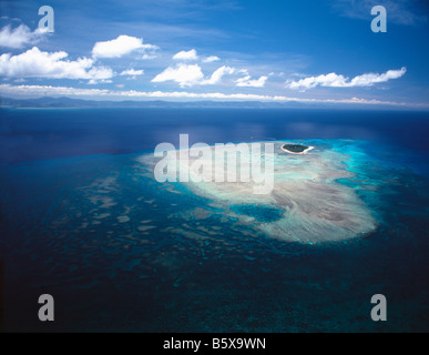 Vista aerea di un bellissimo atollo tropicale con vibranti acque turchesi e una piccola isola nel centro Foto Stock