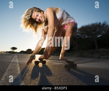 Giovane donna su skateboard accovacciato Foto Stock