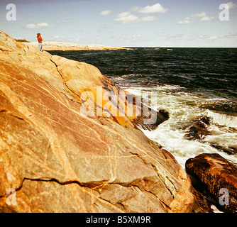 Lungo la costa orientale del Canada, Oceano Atlantico, Nova Scotia persona in piedi sulla roccia guardando verso l'oceano Foto Stock