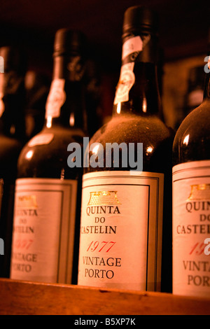 dusty wine bottles on wooden shelf Stock Photo