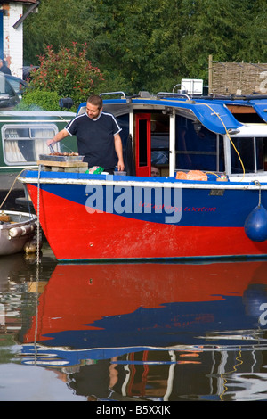 L'uomo la cottura su una narrowboat ormeggiata nel fiume Avon a Stratford upon Avon Warwickshire Inghilterra Foto Stock