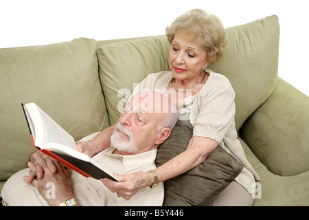 Un anziano uomo prendendo un pisolino di pomeriggio mentre la moglie di letture per lui lo sfondo bianco Foto Stock