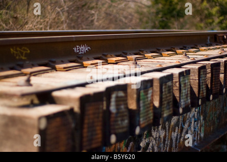 Tag Graffiti e spraypaint sul lato dei binari della ferrovia Foto Stock