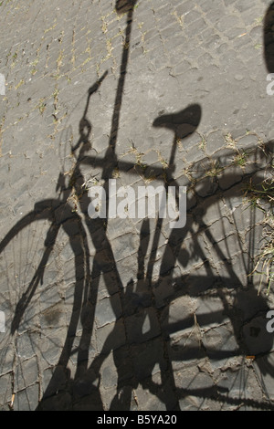 Una bicicletta ombra sul marciapiede strada in sun in italia Foto Stock