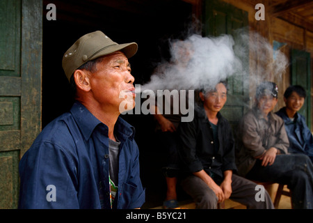 Il vietnamita uomini fumatori tubazione nella parte anteriore della vecchia casa Bac Ha nel Vietnam del Nord Foto Stock