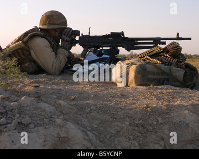 Provincia di Helmand Afghanistan soldato britannico che giace a terra guardando attraverso il binocolo con un obiettivo generale mitragliatrice Foto Stock