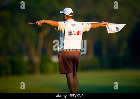 Un caddie tenendo un flag pin su una verde durante il terzo round della 54th Golf World Cup al Olazabal corso in Cina Foto Stock