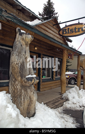 In Cooke City, Montana, dove vivono gli orsi sono visto frequentemente, un orso di legno si erge al di fuori di una città café-bistro Foto Stock