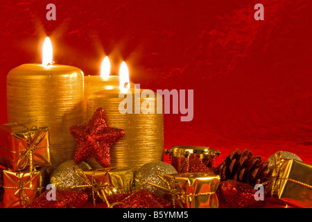 Tre candele accese in una impostazione di Natale con decorazioni stagionali Foto Stock