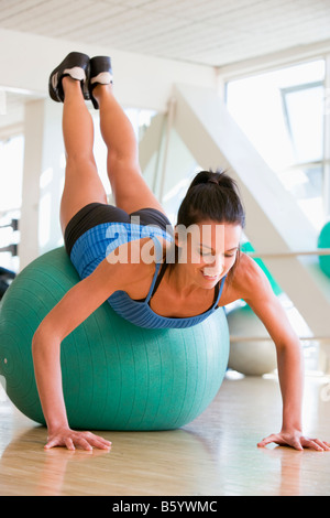 Donna facendo spingere Ups sulla sfera svizzero in palestra Foto Stock