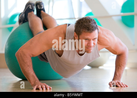 Uomo in equilibrio su Swiss Ball alla Palestra Foto Stock