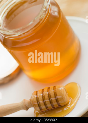 Un vasetto di miele e cucchiaio Foto Stock