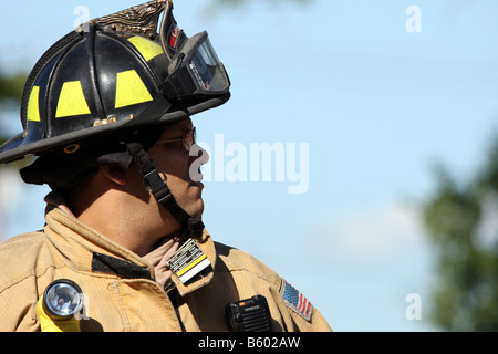 Leader di un team fire fighter profilo con stati di tag per la sua uniforme per tenere traccia di quelle dei vigili del fuoco coinvolti in caso di emergenza Foto Stock