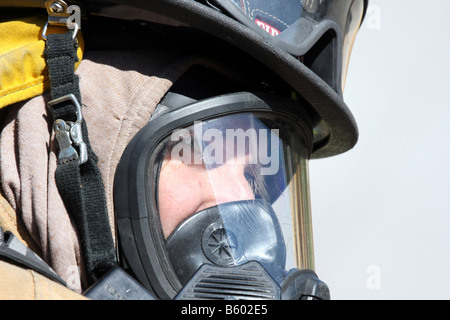 Una chiusura di un vigile del fuoco del peering attraverso la sua maschera di respirazione per vedere un altro pompiere Foto Stock