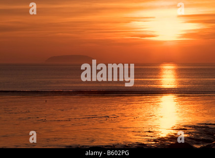 Vivace tramonto arancione sulle distese fangose di Sandpoint vicino a Weston-super-Mare, con Steepholm Island visibile all'orizzonte. Foto Stock