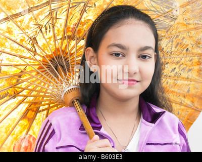 Una bella ragazza asiatica sorridente e tenendo un tradizionale ombrello orientale Foto Stock