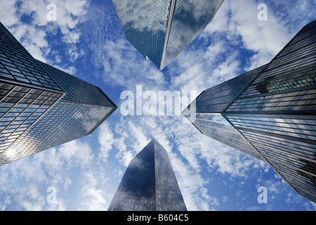 Guardando in alto attraverso quattro alti grattacieli di vetro a Manhattan per una potrebbe riempito il cielo. Foto Stock