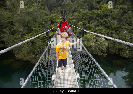 Famiglia a piedi la Abel Tasman via costiera a Falls River sospensione ponte Nelson regione Isola del Sud della Nuova Zelanda Foto Stock