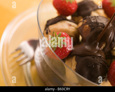 Profiterole al cioccolato con fragole e salsa al cioccolato Foto Stock