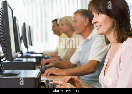 Quattro persone sedute a terminali di computer (profondità di campo/high key) Foto Stock