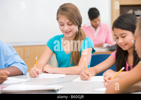 Gli studenti nella classe iscritto con l insegnante di sfondo (il fuoco selettivo) Foto Stock