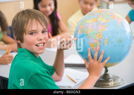 Studente in classe rivolto al mondo con gli studenti di sfondo (il fuoco selettivo) Foto Stock